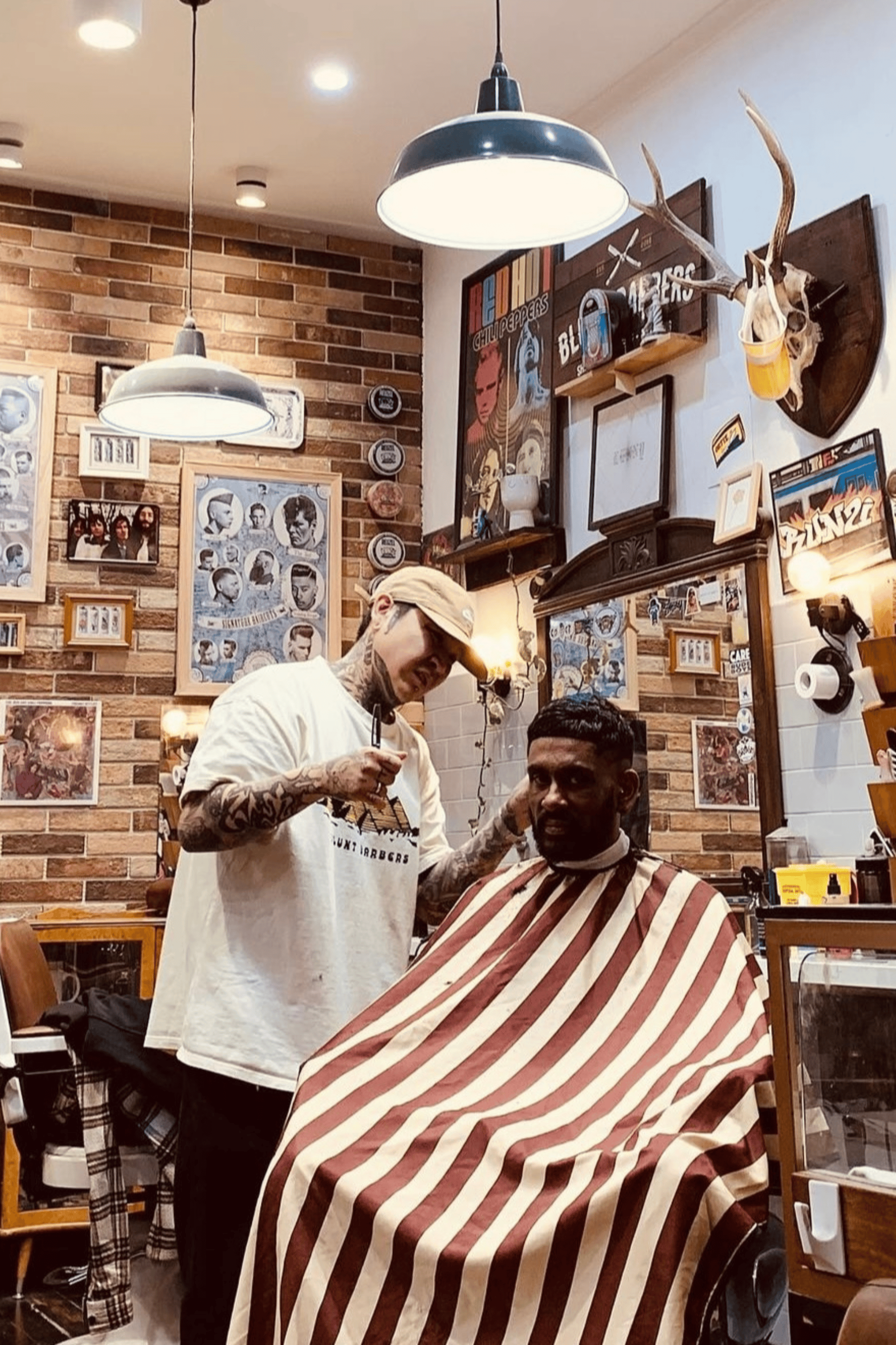 barber cutting clients hair inside traditional barbershop using Burgundy Banded Cutting Cape