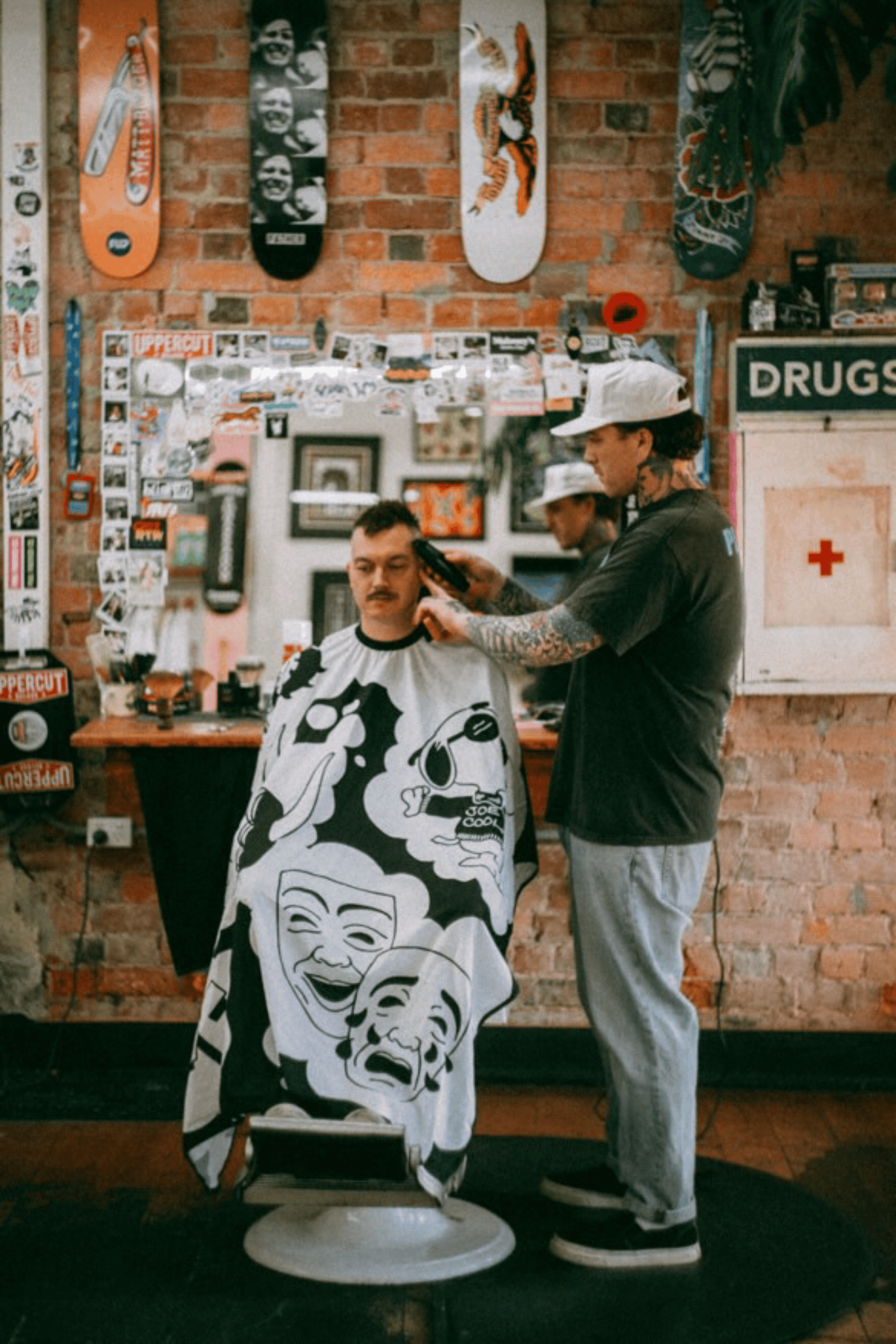 Jimmy's Barbershop cutting customer hair using Love Hate Barber Cape in black and white