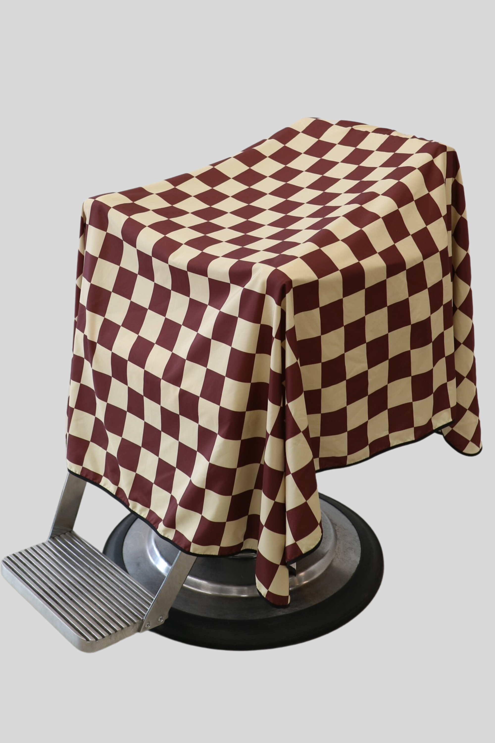 burgundy and tan checker barber cape draped on barbershop chair