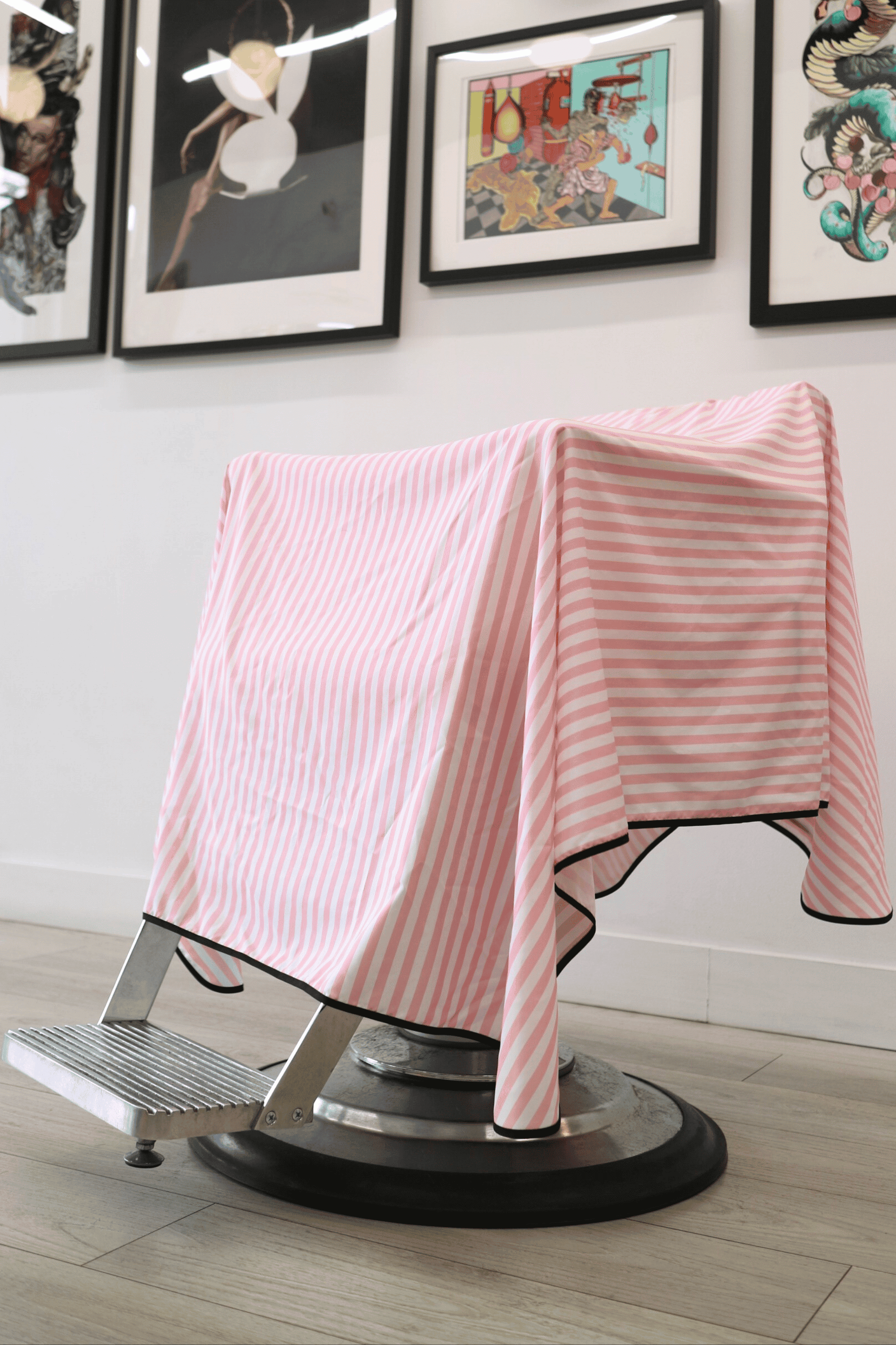 close up of pink and white stripe barber cutting cape on chair