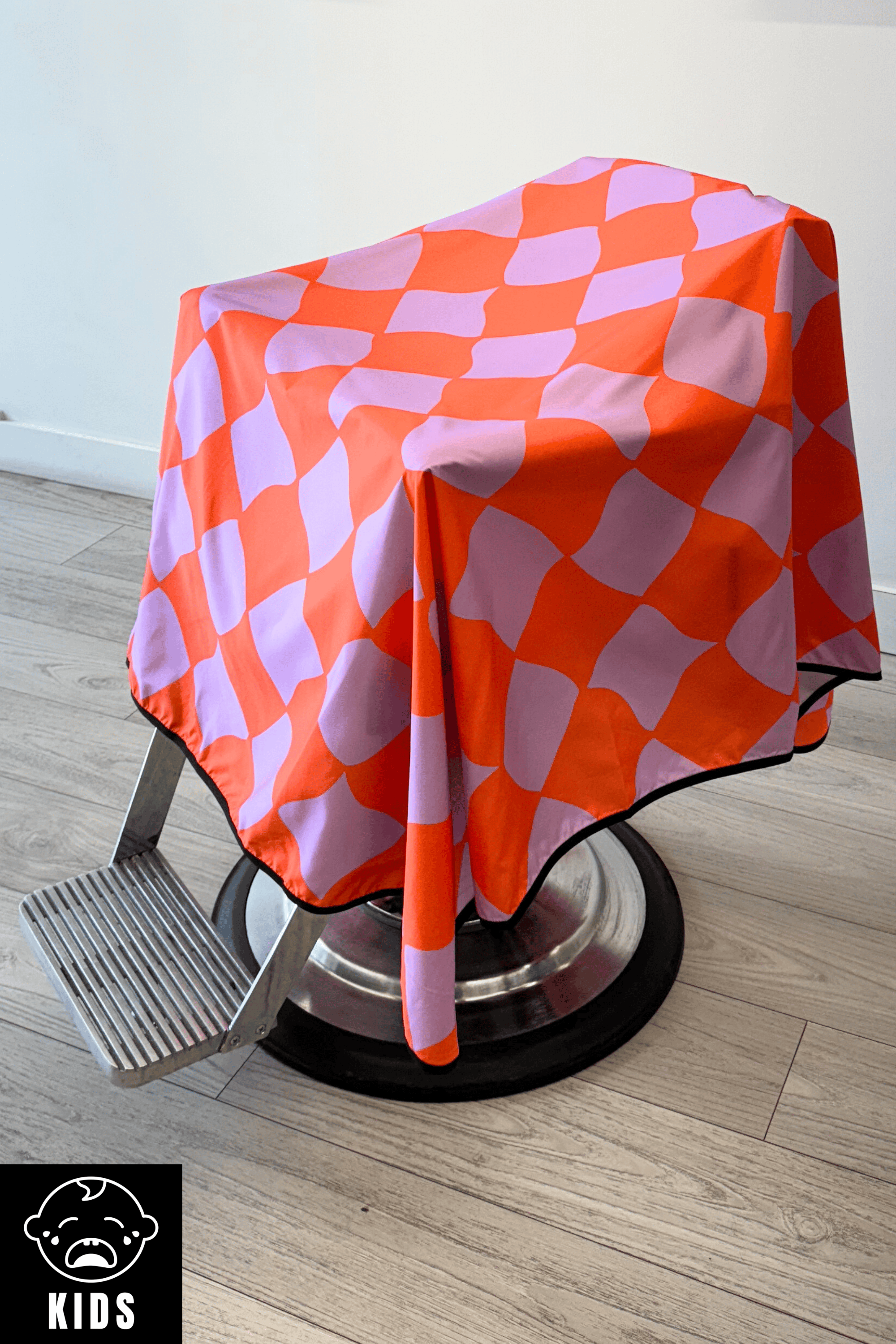 side shot of a the funhouse barber cape draped on barber chair