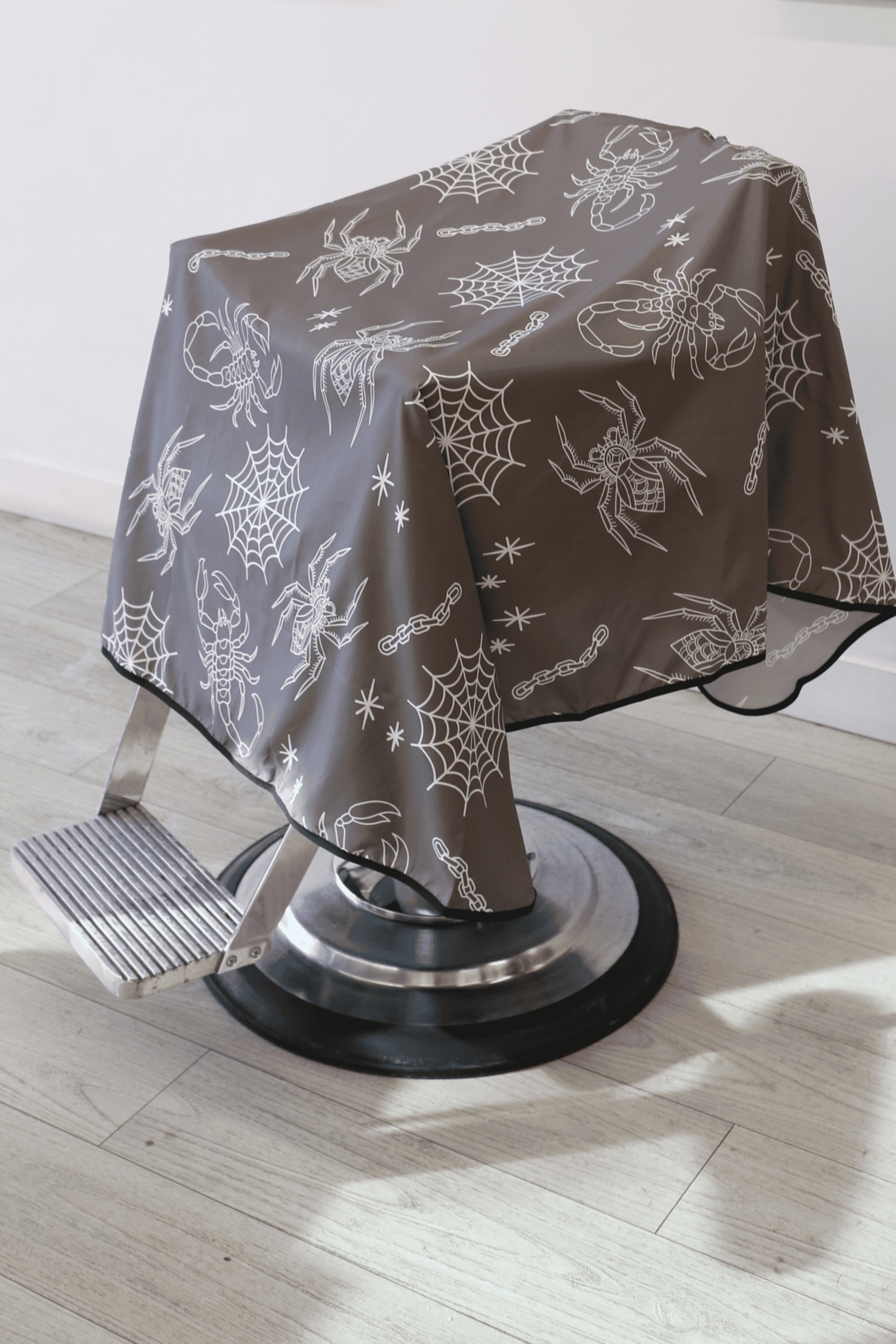 a grey and white tattoo flash barber cape on barber chair