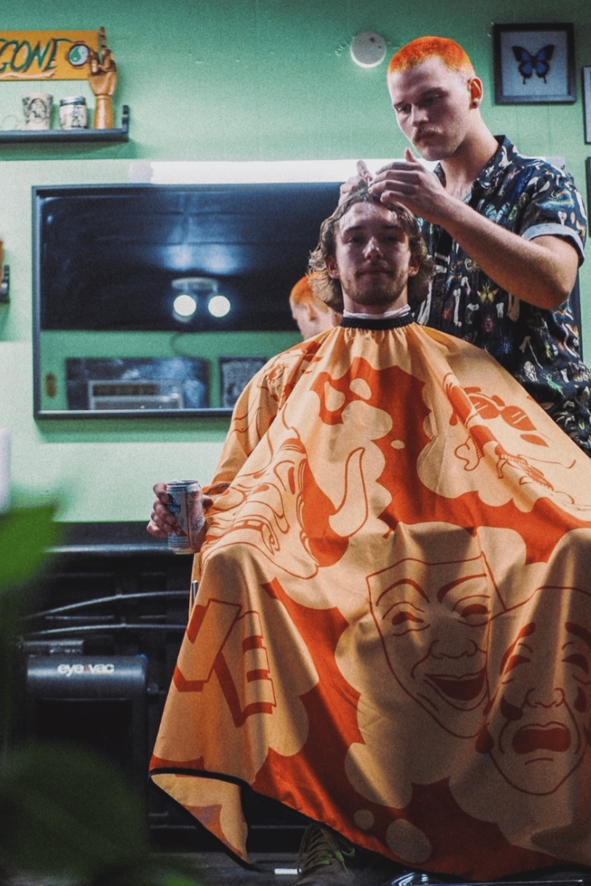 barber cutting customer hair inside barbershop using orange love hair barbershop with cartoon imagery