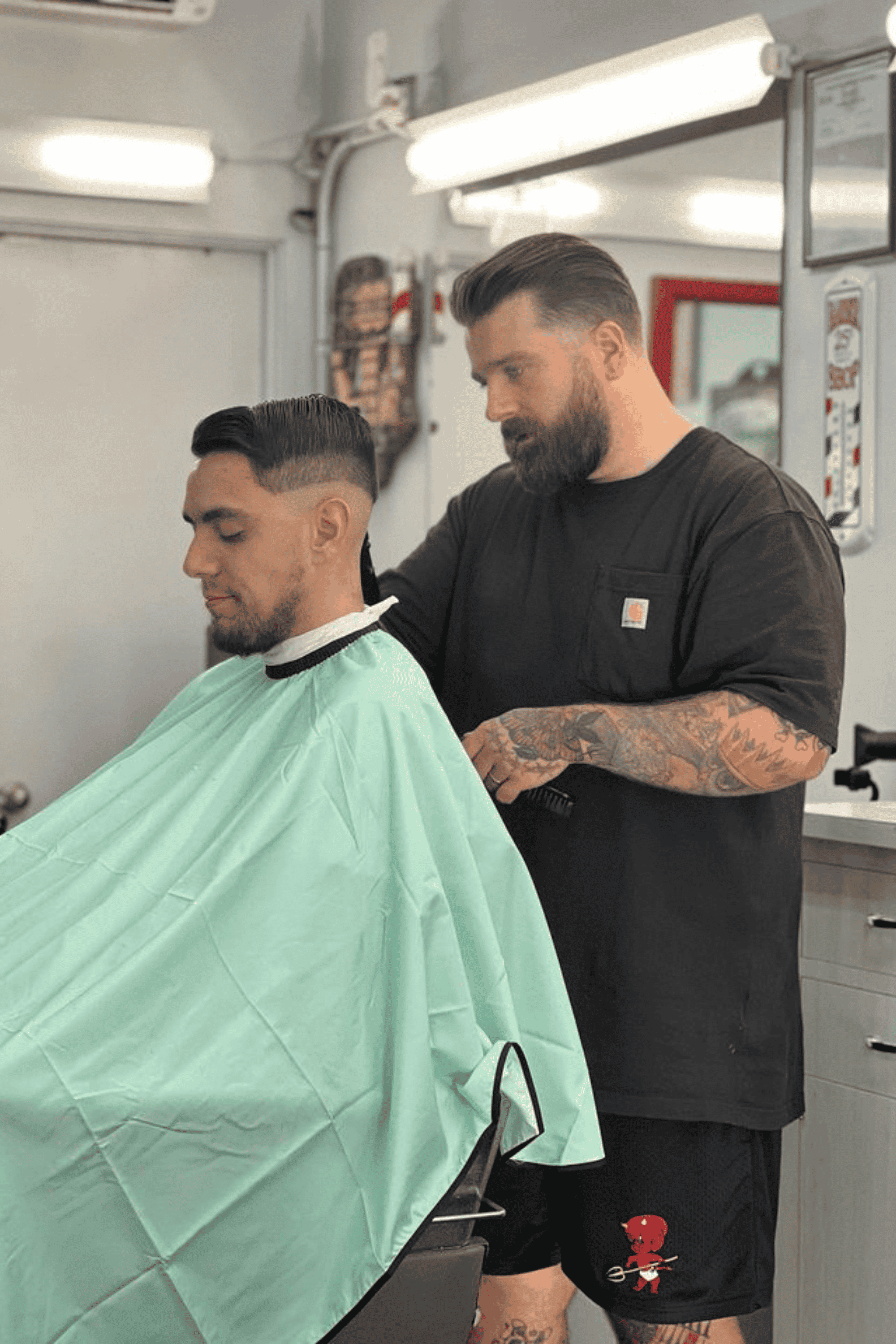 barber cutting male clients hair using the mint barber cape inside a barbershop