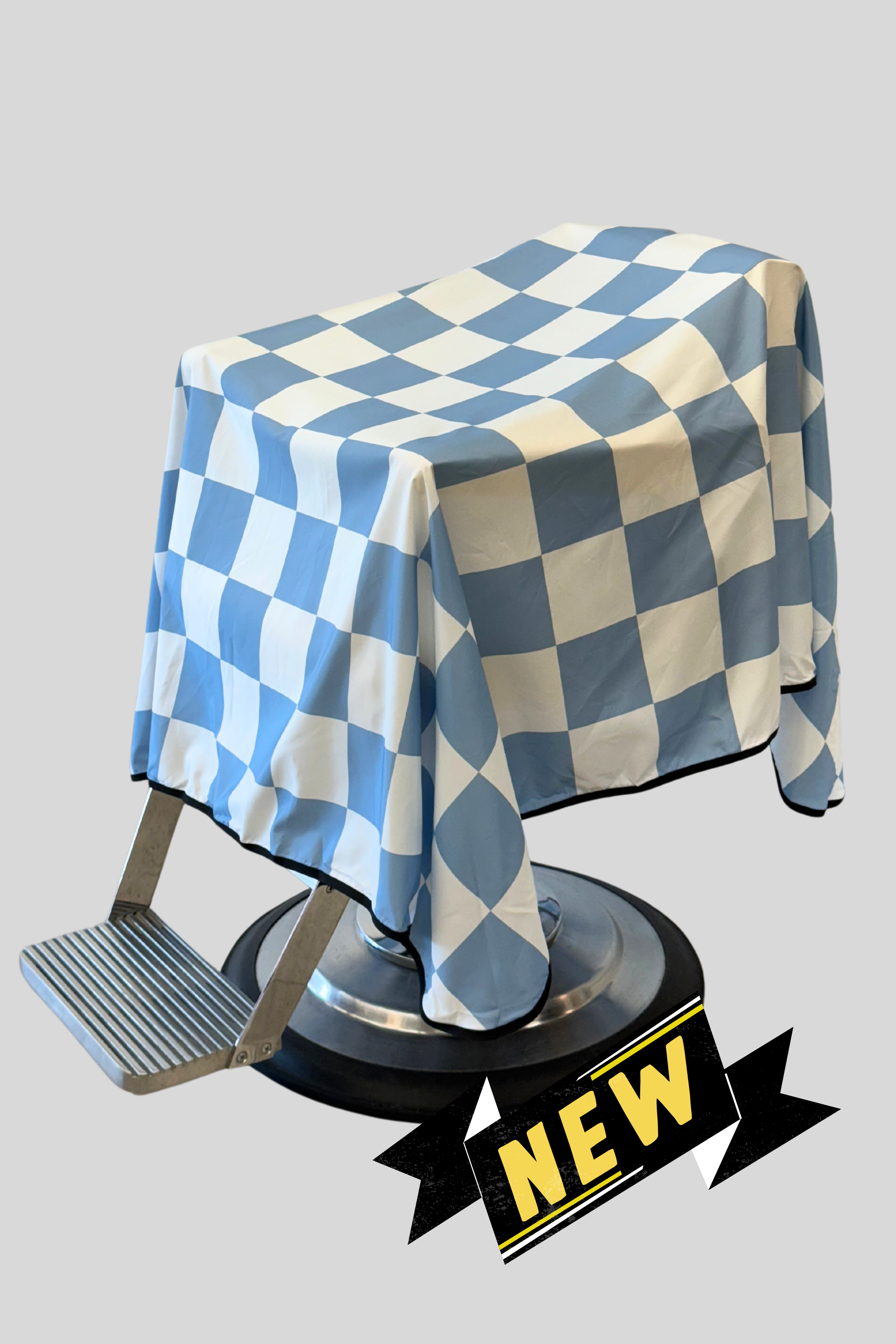 baby blue and white large format checker cape draped on barber chair with "NEW "banner