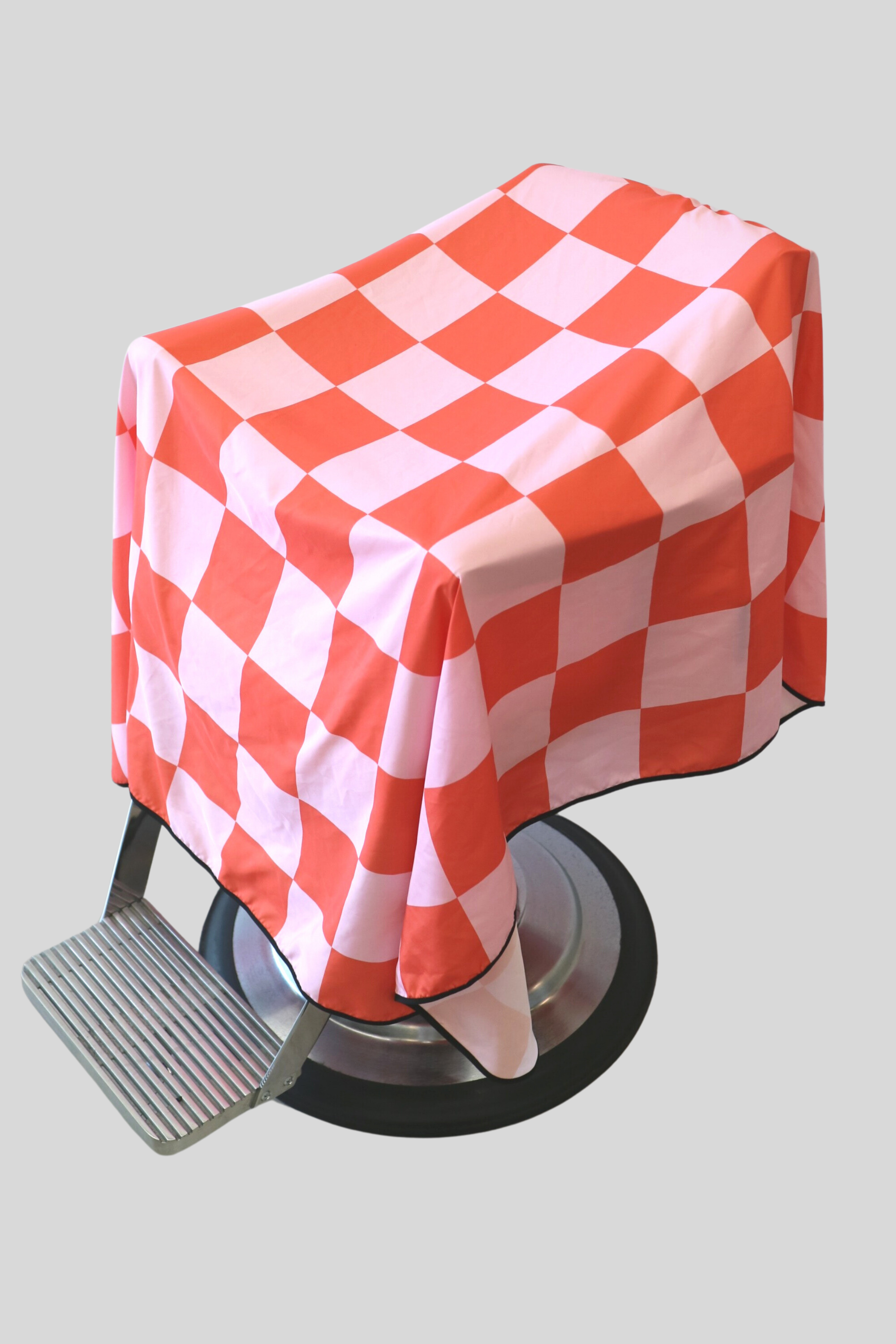 pink and red checker rally v2 barber cape draped on barbershop chair