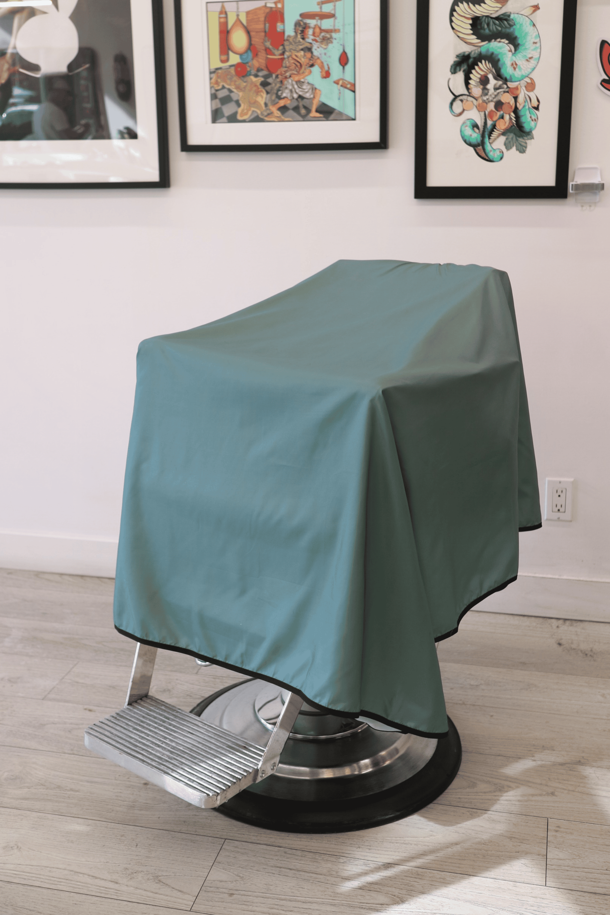 sage colored barber cutting cape draped on barber chair inside a barbershop