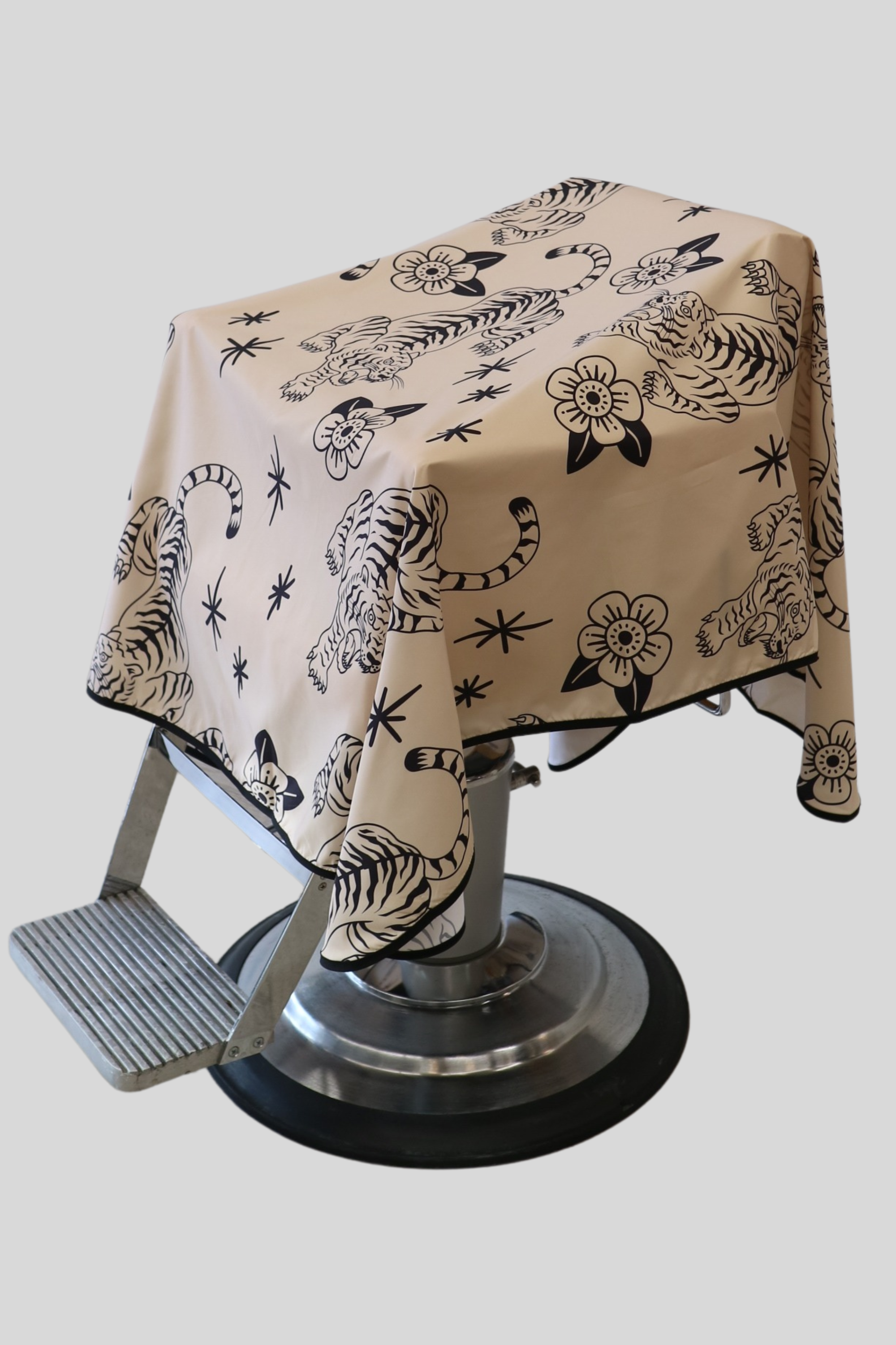 cream and black tora barber cape draped on a barber chair