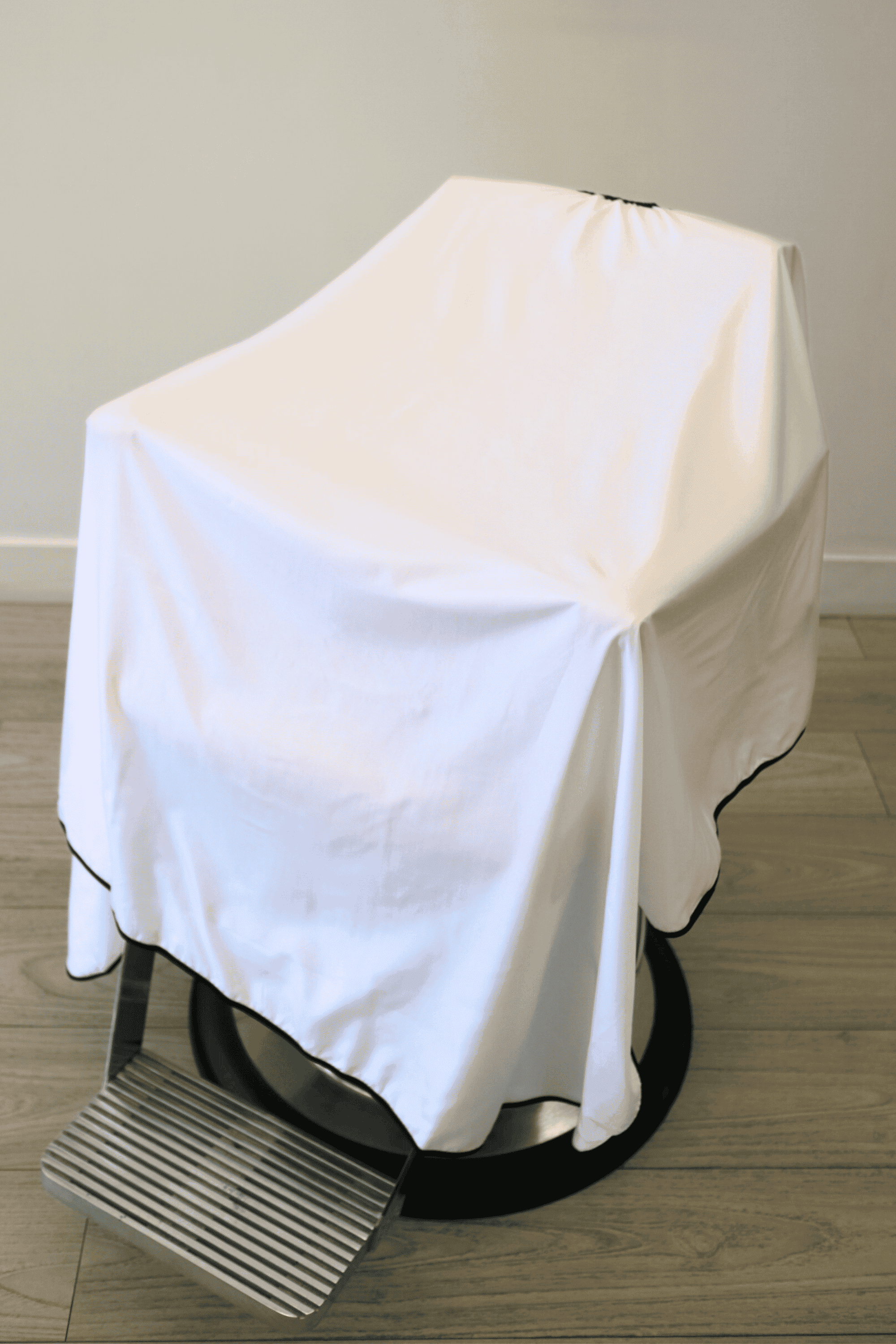 close up of white barber cutting cape draped on barber chair