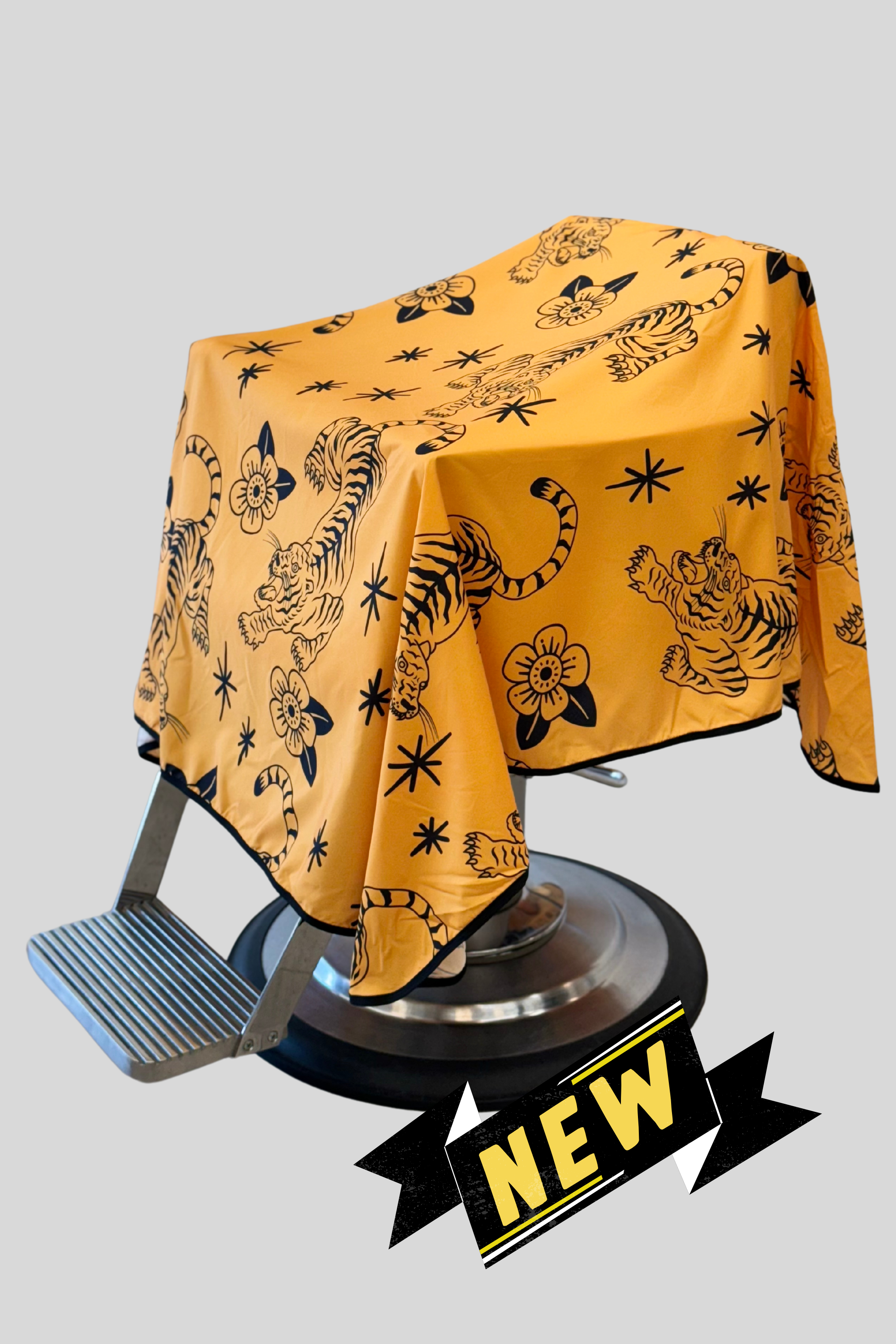 yellow and black tora barber cape draped on chair with "new" banner